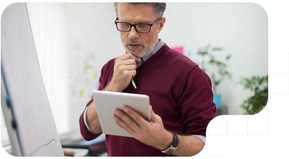Professional analyzing data on a tablet in front of a whiteboard