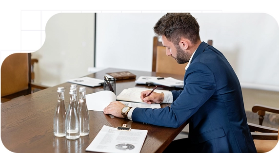Man reviewing and signing documents at a meeting table.